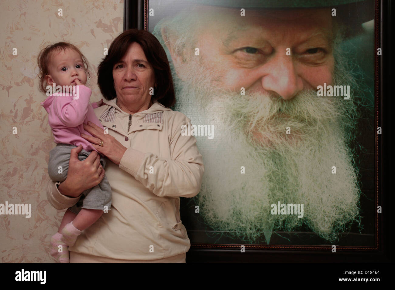 Une religieuse juive tient ici le petit-fils alors qu'elle se tient à côté d'un grand portrait du rabbin Menachem Mendel Schneerson qui était un chef du mouvement Chabad-Lubavitch un mouvement juif orthodoxe hassidique. Israël Banque D'Images