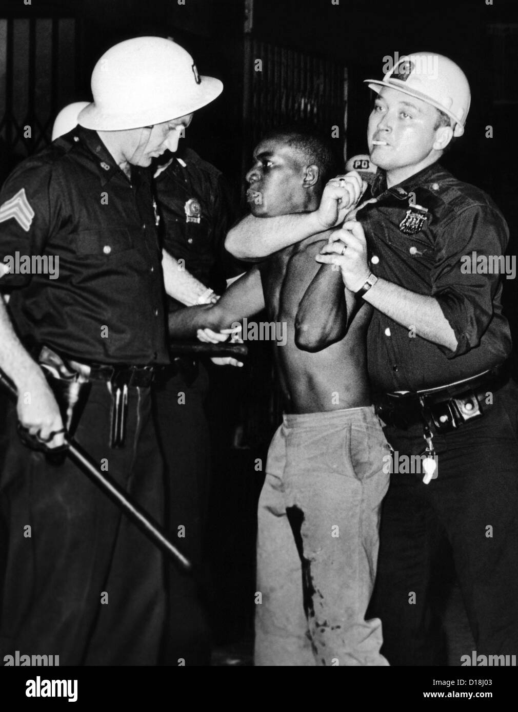 African American qui a été touché à la jambe, est retenu par la Police de la ville de New York. Il aurait jeté les bouteilles de bière en direction de la police Banque D'Images