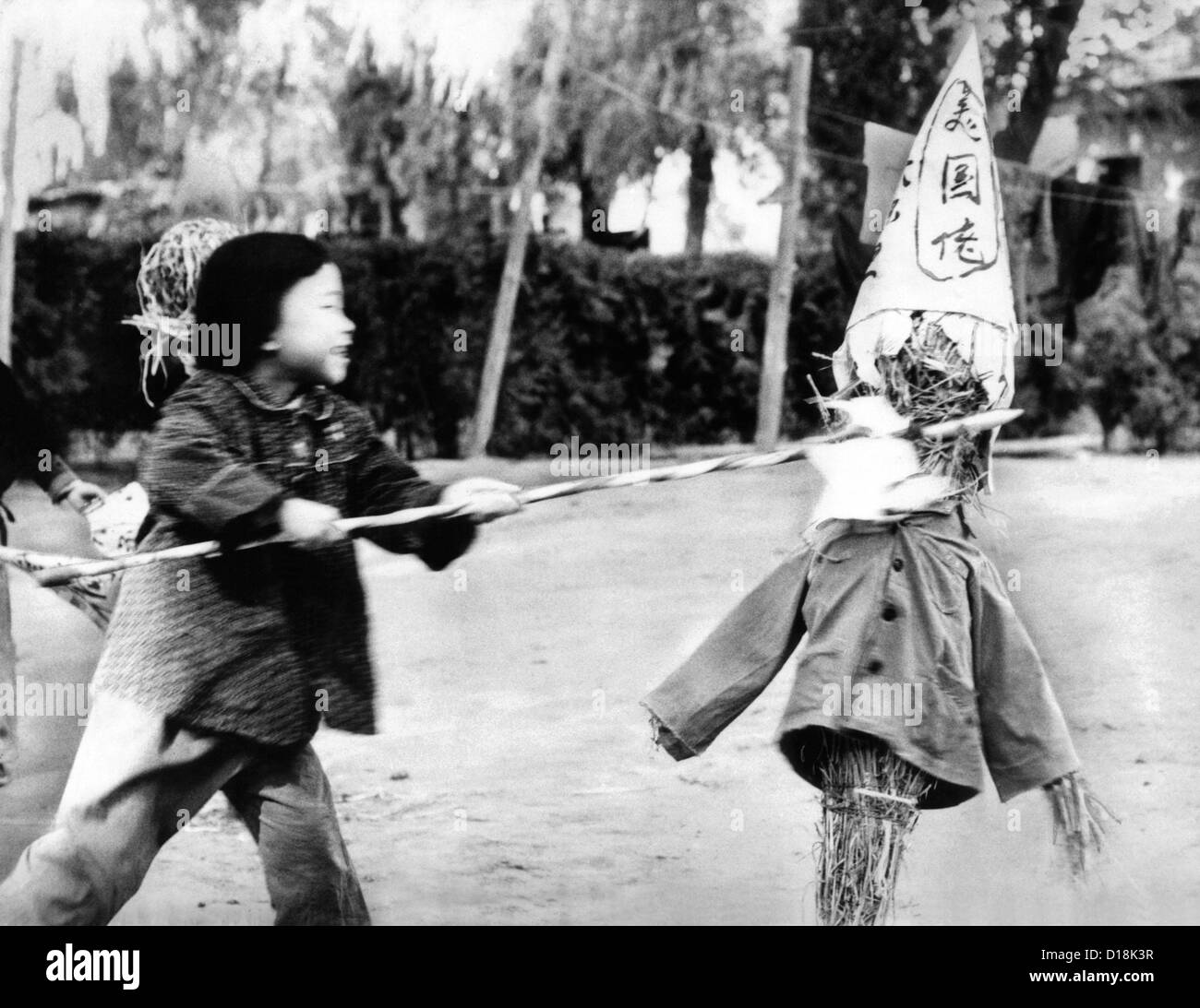 Un jardin d'une petite fille chinoise lance dans une effigie de paille marqué d'un signe, ce qui peut être traduit approximativement par "US bad Banque D'Images