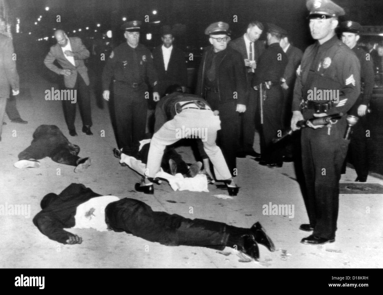 Les musulmans noirs bataille avec la police de Los Angeles. Un officier garde son fusil de chasse à l 'prêt' que les ambulanciers ont tendance à musulman noir Banque D'Images