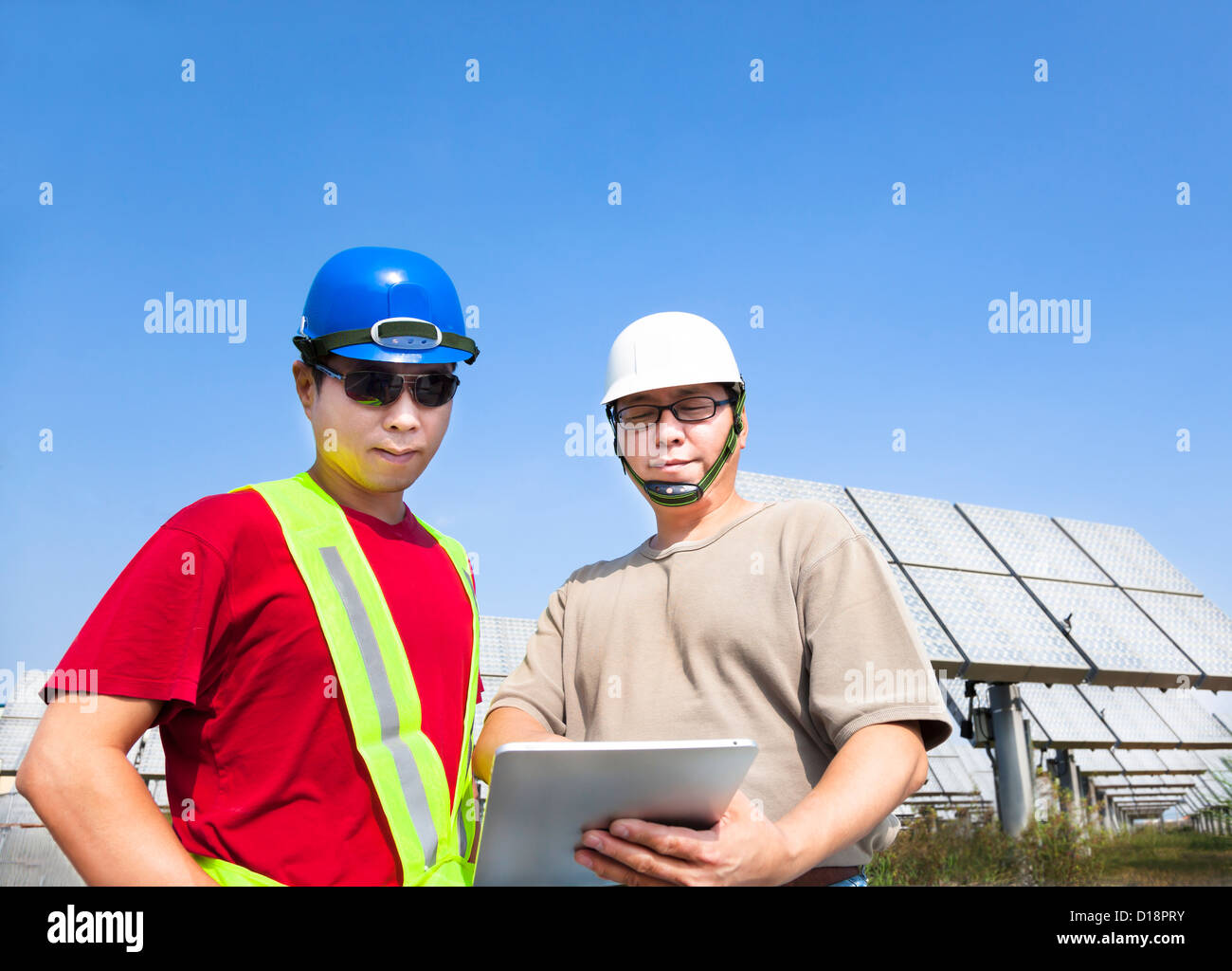 Deux entrepreneurs holding tablet pc et debout devant le panneau solaire Système de suivi Banque D'Images