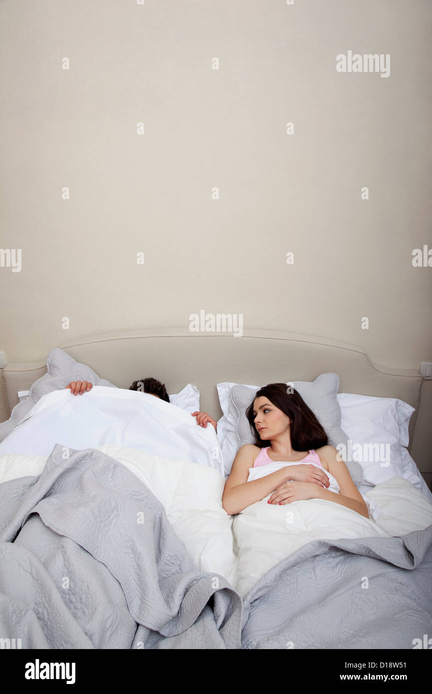Couple in bed, l'homme de se cacher sous une couette Photo Stock - Alamy