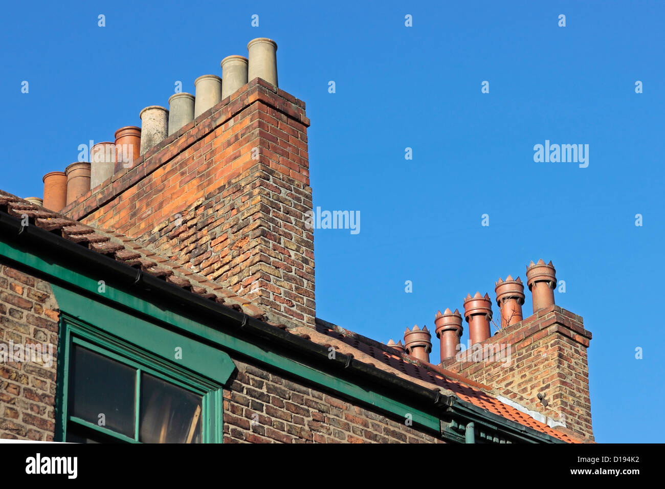 Vieux pots de cheminée sur un toit Selby contre un ciel bleu clair Banque D'Images