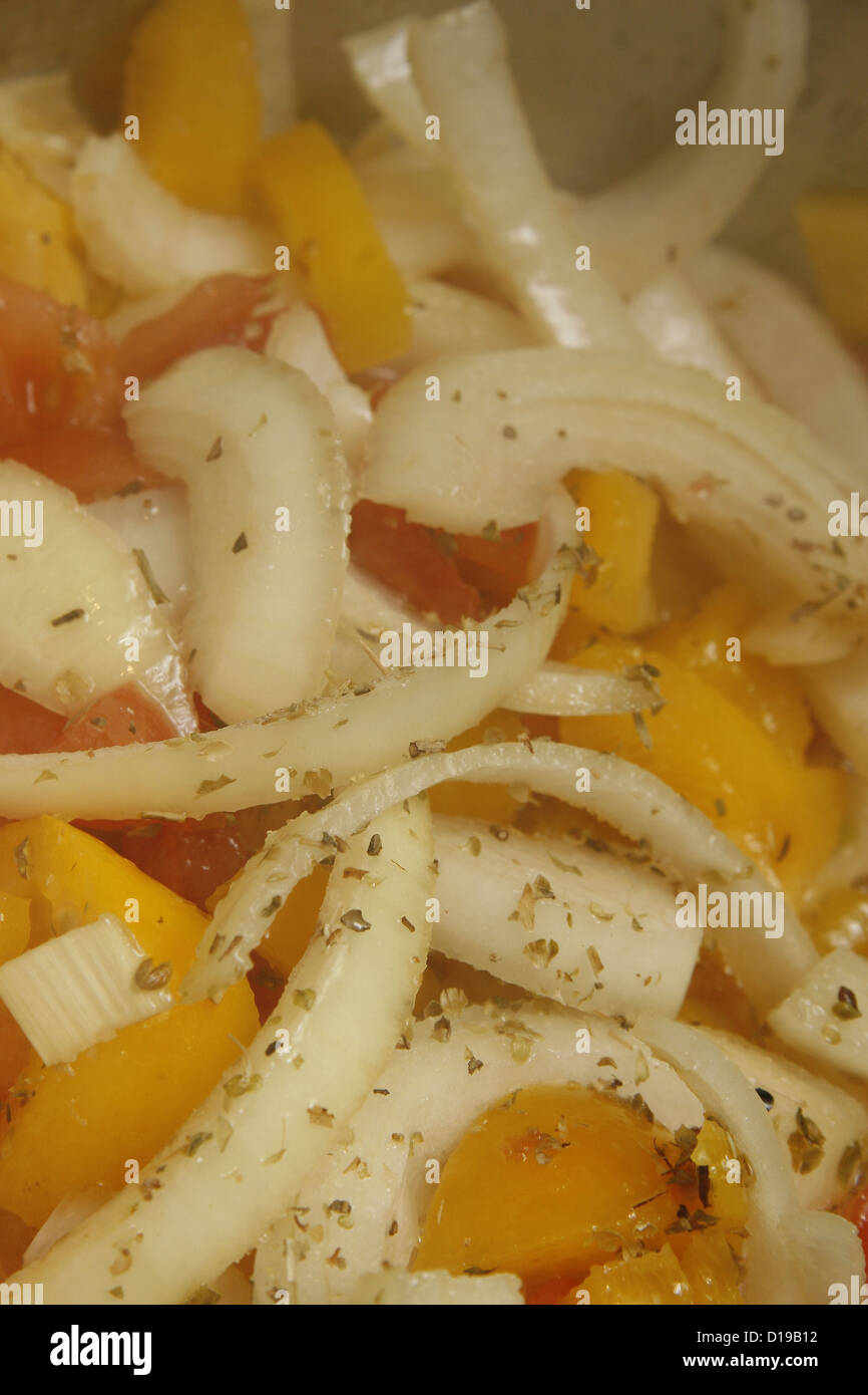 Poivrons jaunes haché et oignons blancs couverts dans la cuisine d'origan séché dans une casserole Banque D'Images