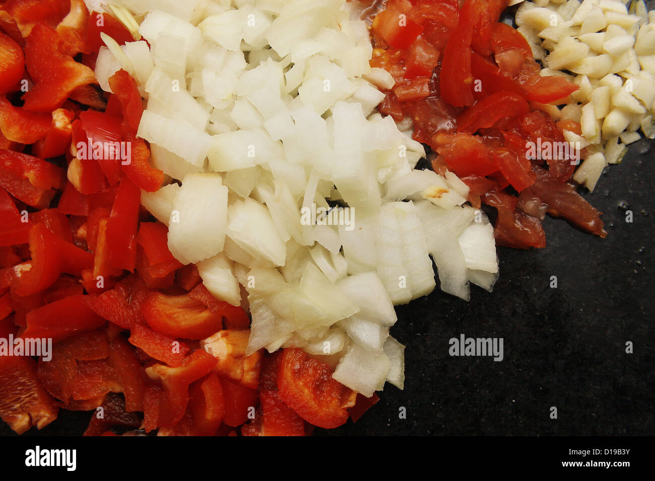Pyramide alimentaire de poivrons, oignons, tomates et ail sur en planche à découper Banque D'Images