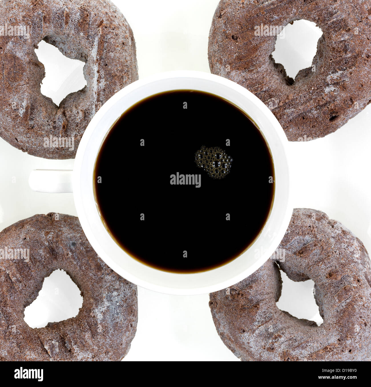Une tasse de café noir avec quatre beignets sur une plaque blanche. Banque D'Images