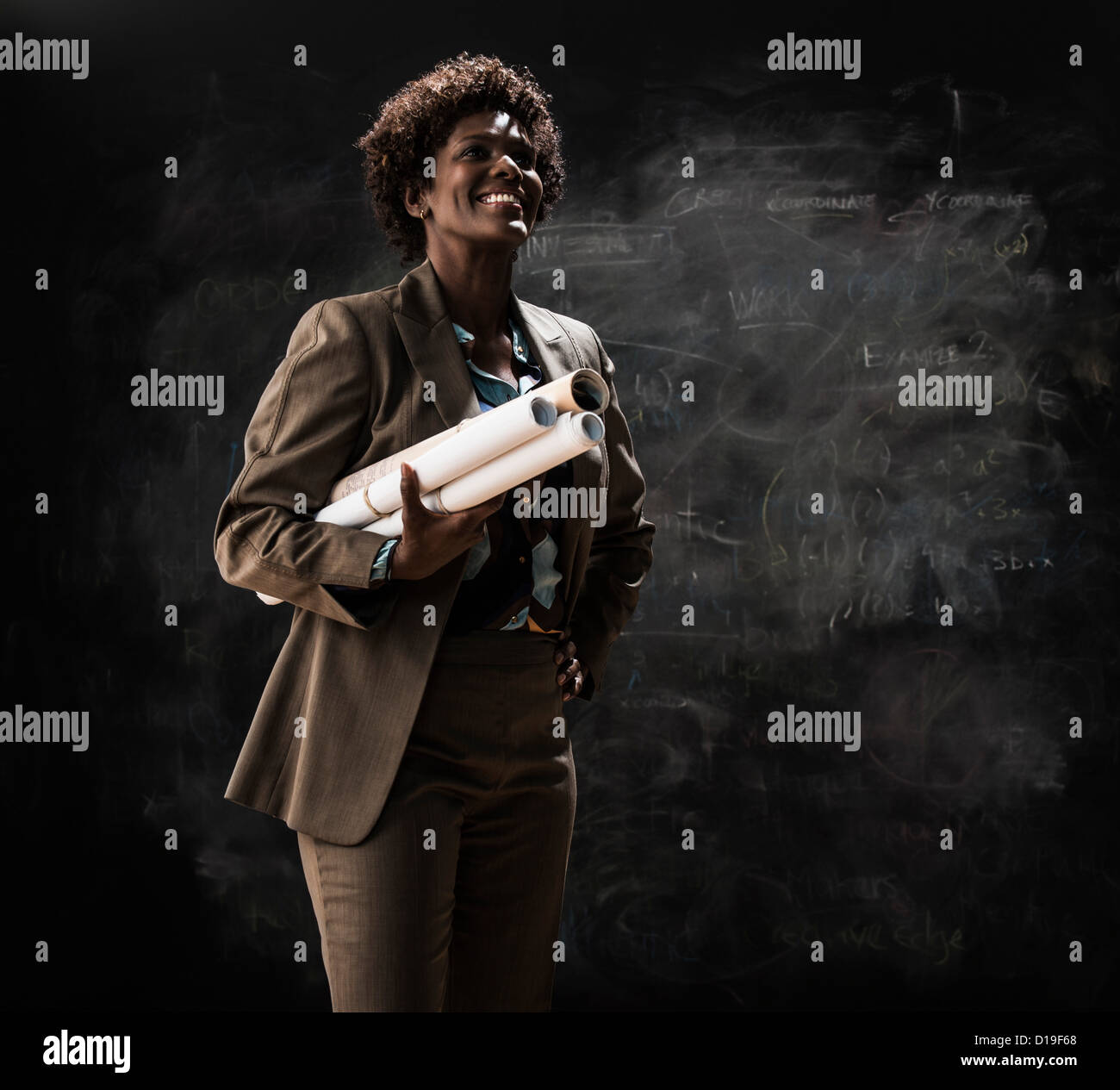 Businesswoman holding blueprint par blackboard Banque D'Images