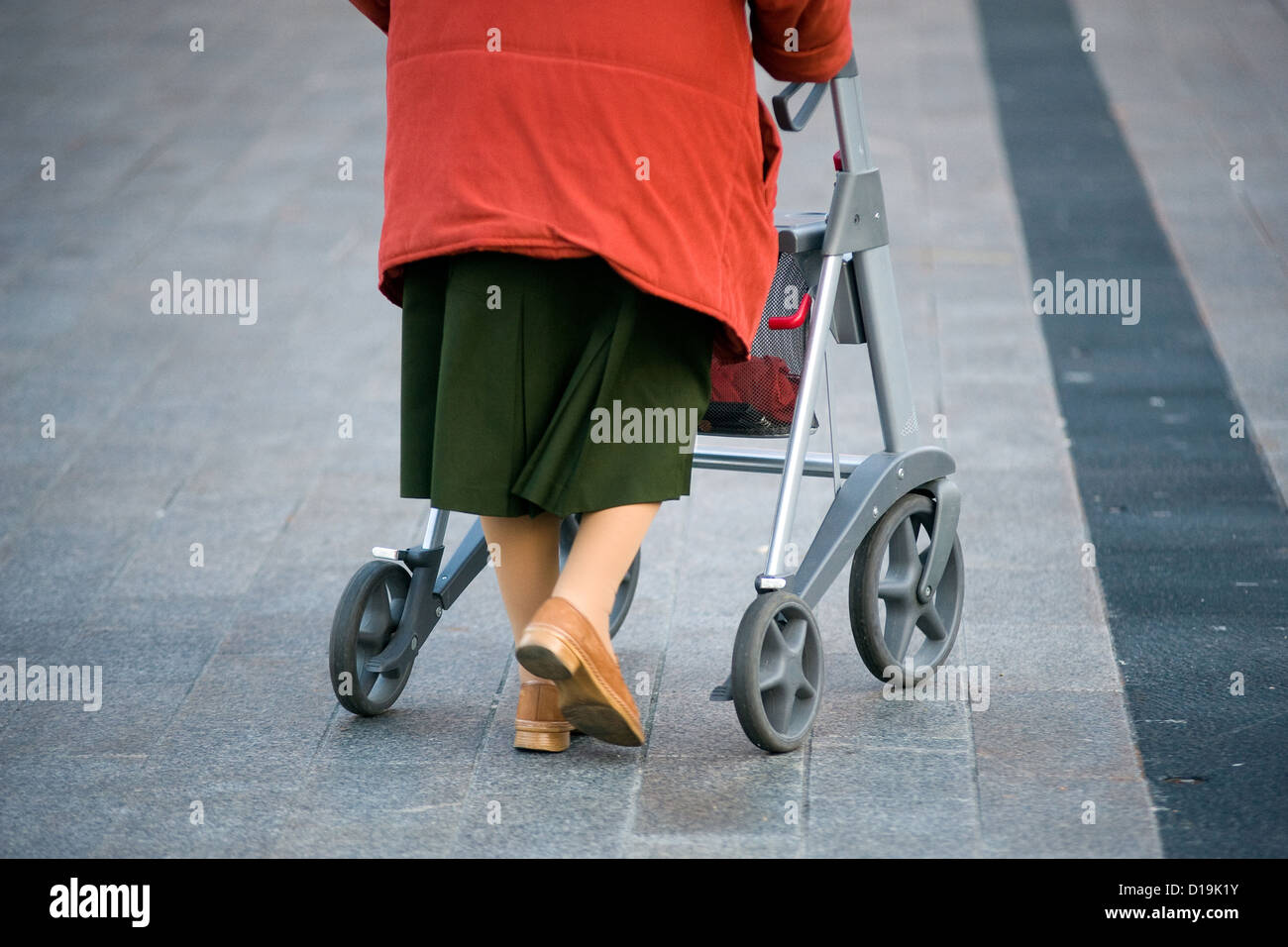 Une vieille femme marche dans la rue avec son déambulateur Banque D'Images