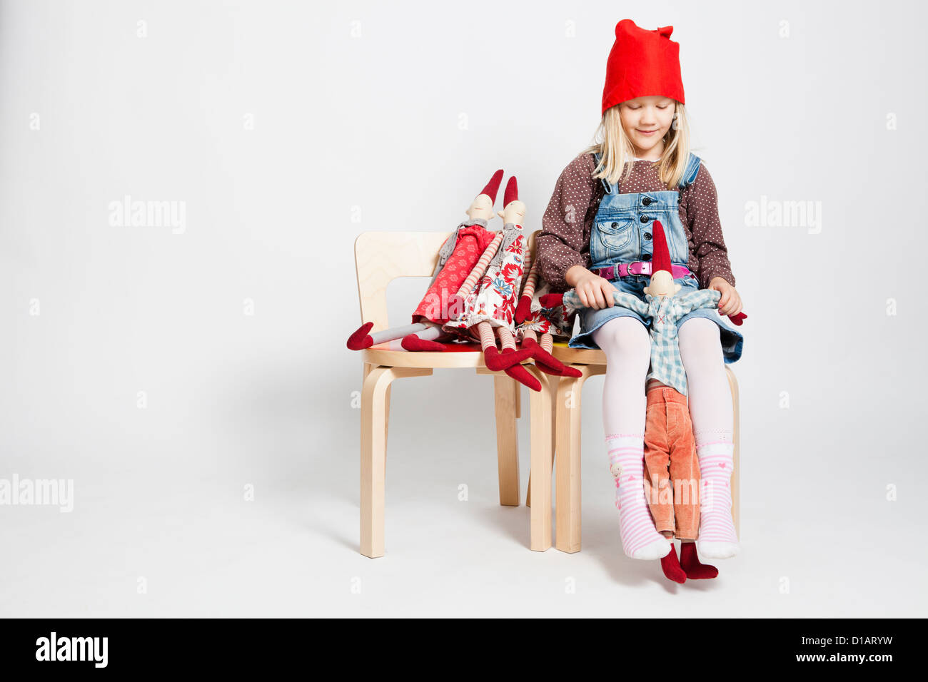 Studio portrait of happy young girl sitting on chair et en jouant avec des poupées jouet lutin de Noël Banque D'Images