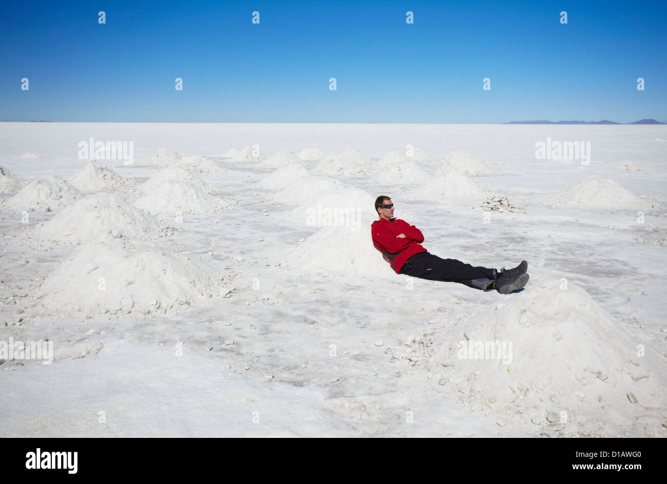 Homme assis à côté de tas de sel sur le Salar de Uyuni (Salines d'Uyuni), Potosi, Bolivie Ministère Banque D'Images
