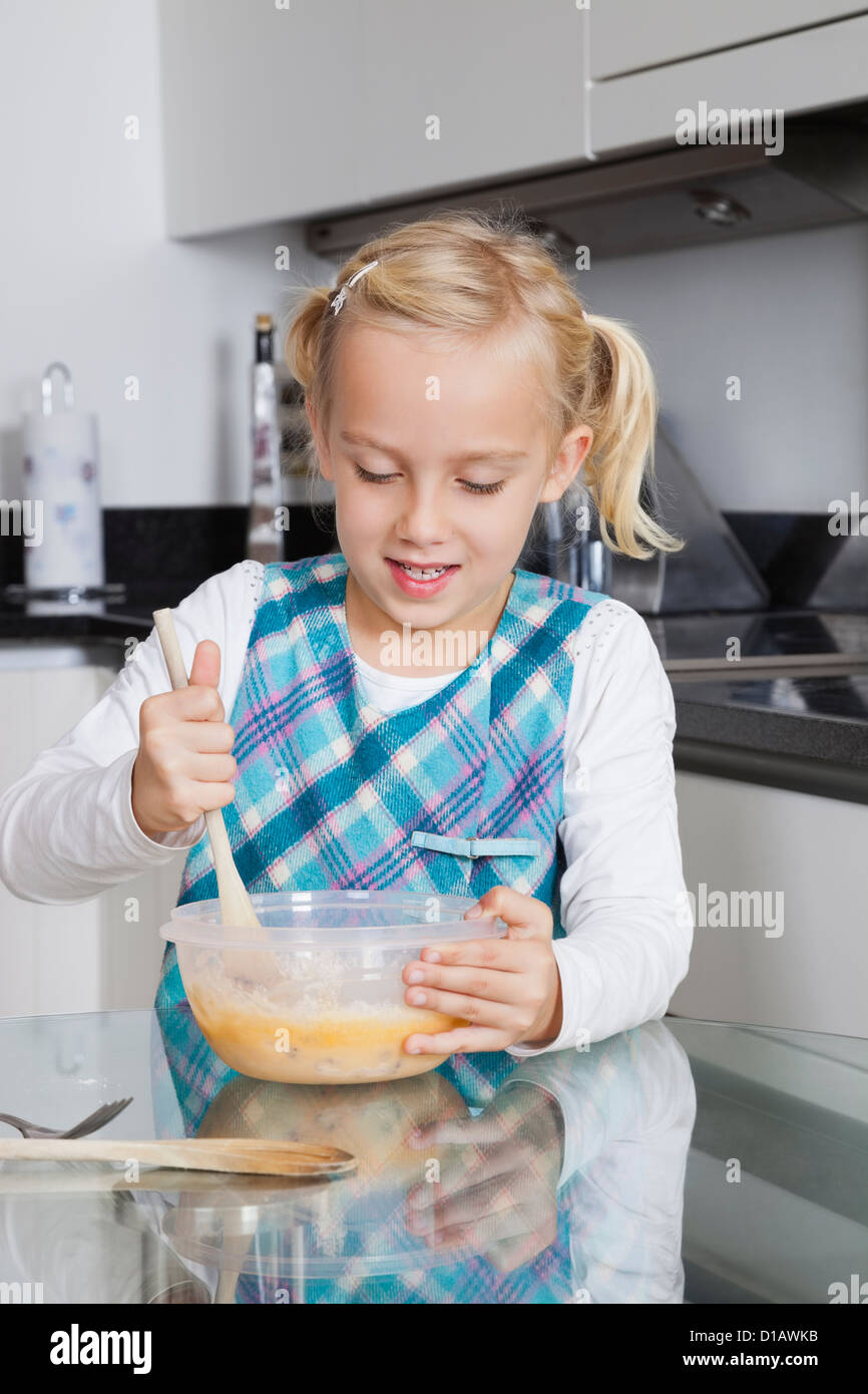 Girl making cookies dans un bol à mélanger en cuisine Banque D'Images