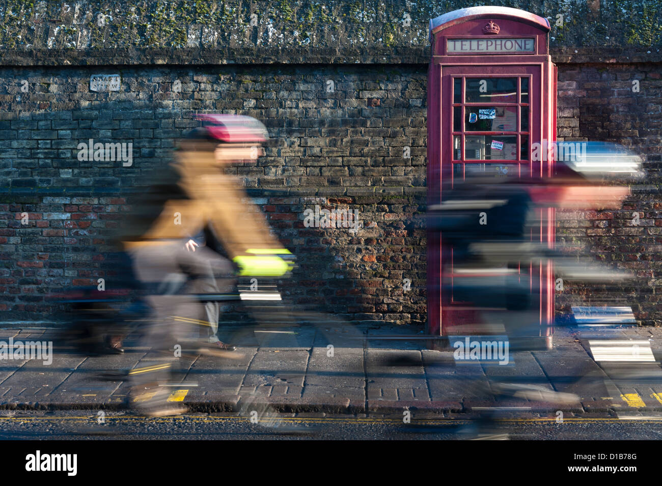 Les cyclistes avec le flou en passant un téléphone rouge traditionnel fort Regent Street Cambridge UK Banque D'Images