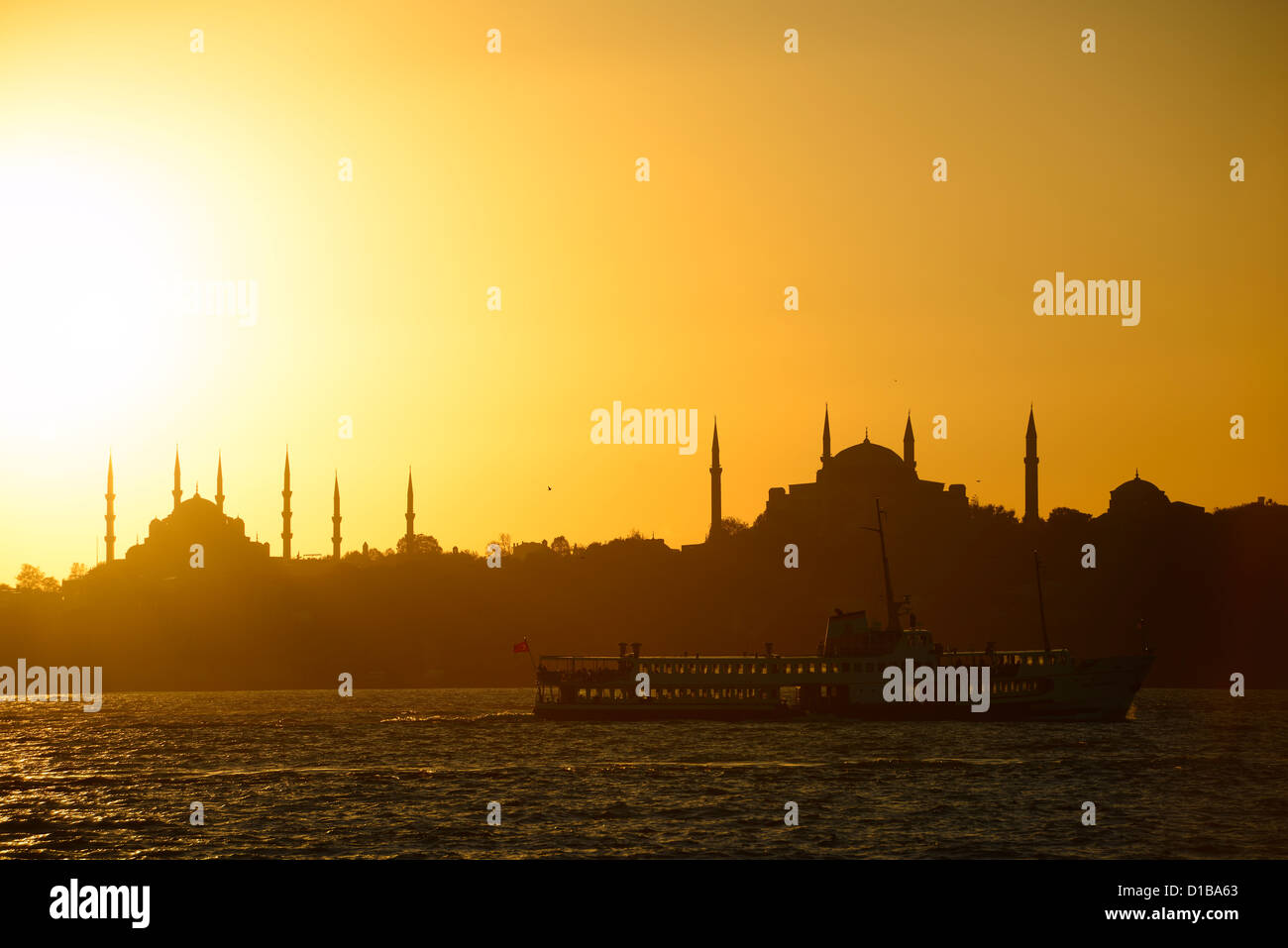 Ciel d'or avec la Mosquée Bleue et Sainte-Sophie minarets silhouettes au coucher du soleil sur le Bosphore avec bus de mer Istanbul Turquie Banque D'Images