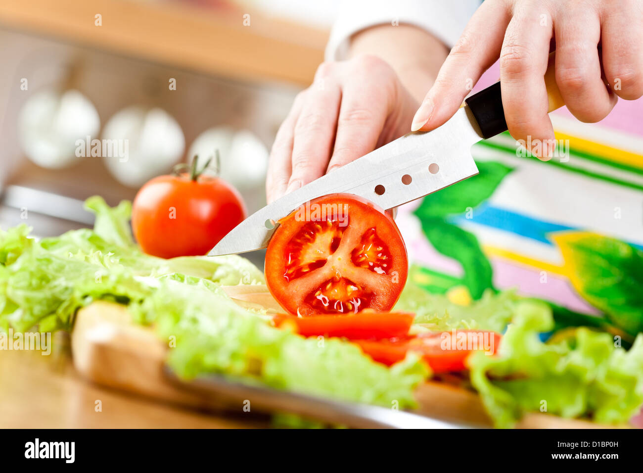 Woman's hands cutting tomate, derrière les légumes frais. Banque D'Images