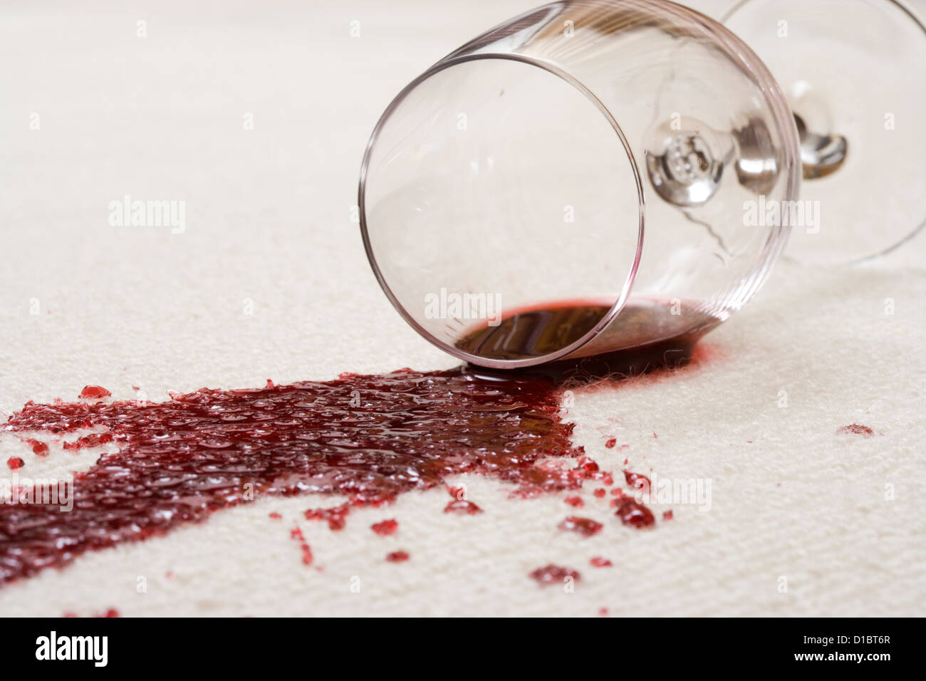 Vin rouge renversé sur le tapis. Banque D'Images