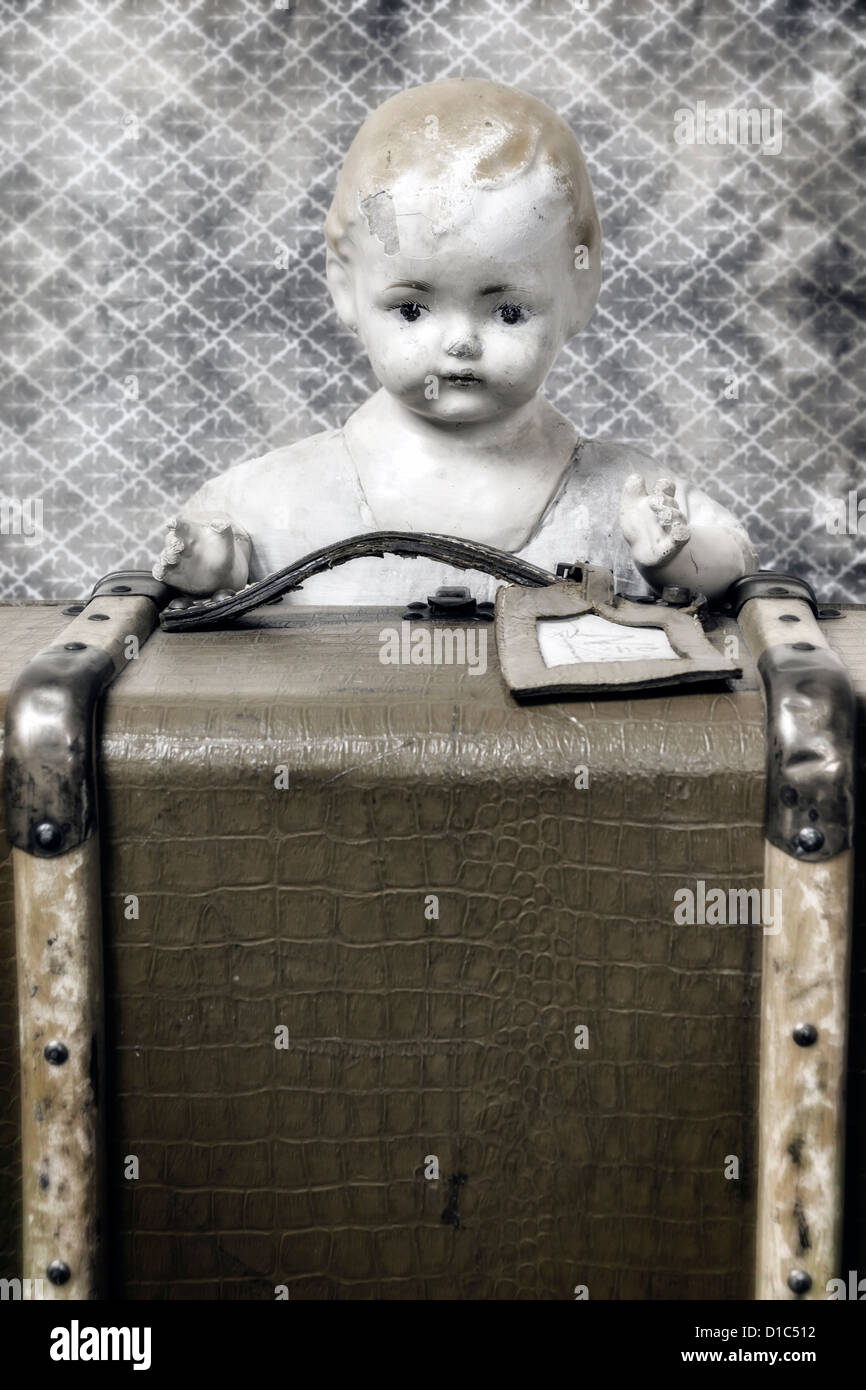 Une vieille poupée est à la recherche d'une valise vintage Banque D'Images