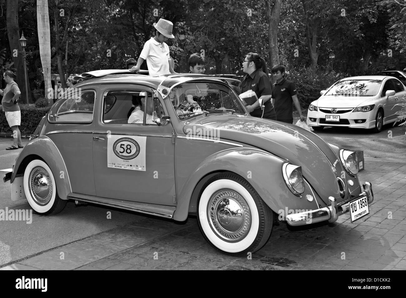 Volkswagen Beetle '50 et les passagers à un rallye de voitures anciennes. S. E. Asie Thaïlande la photographie noir et blanc Banque D'Images