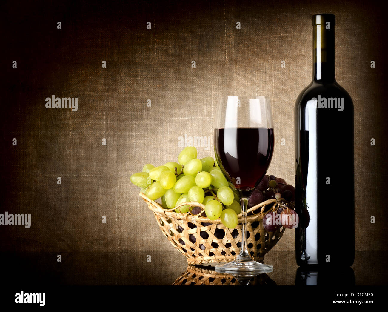 Bouteille de vin rouge et les raisins sur une toile de fond Banque D'Images