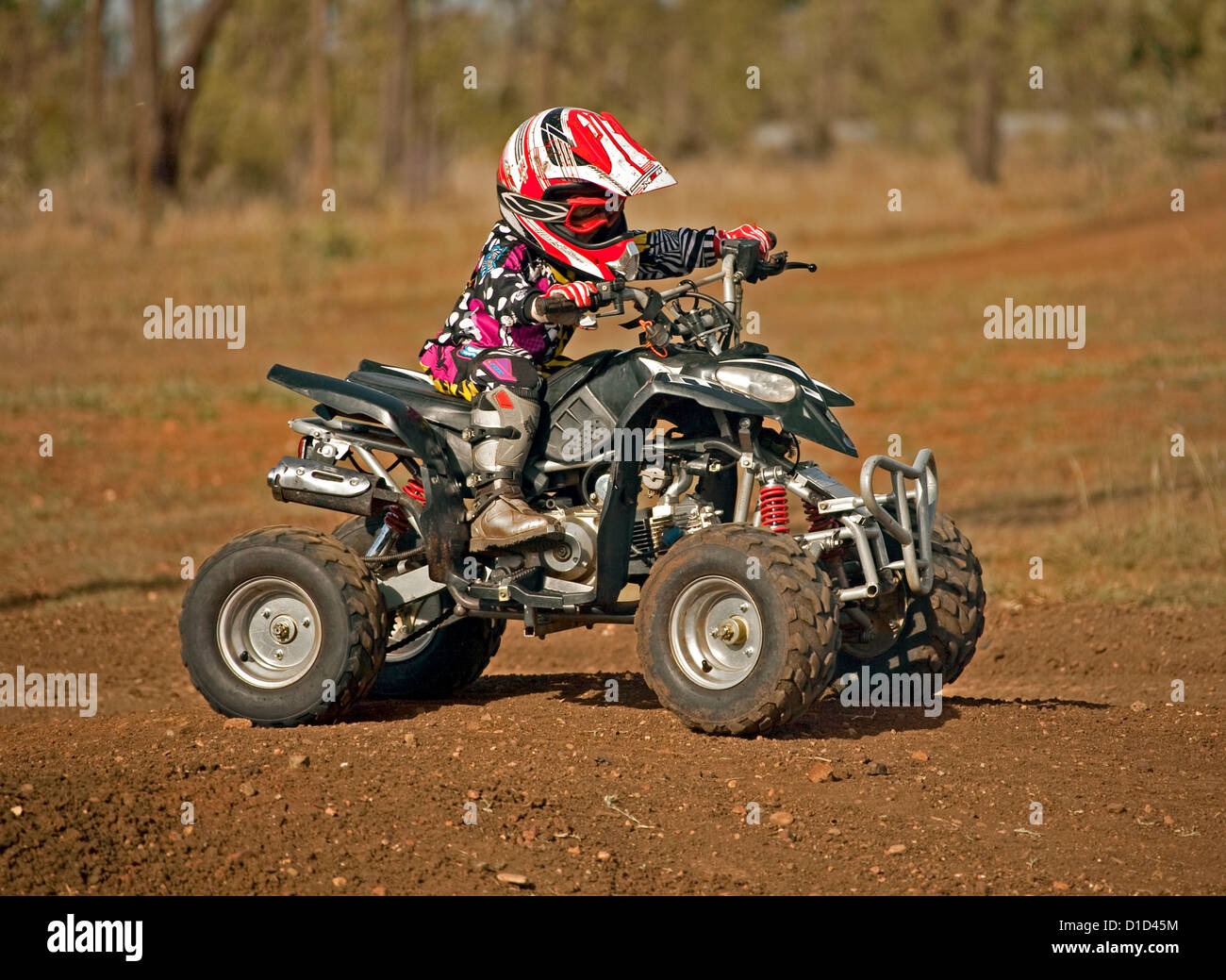 Jeune enfant - 4 ans - quad sur le port de vêtements protecteurs et l'équitation sur un chemin de terre Banque D'Images