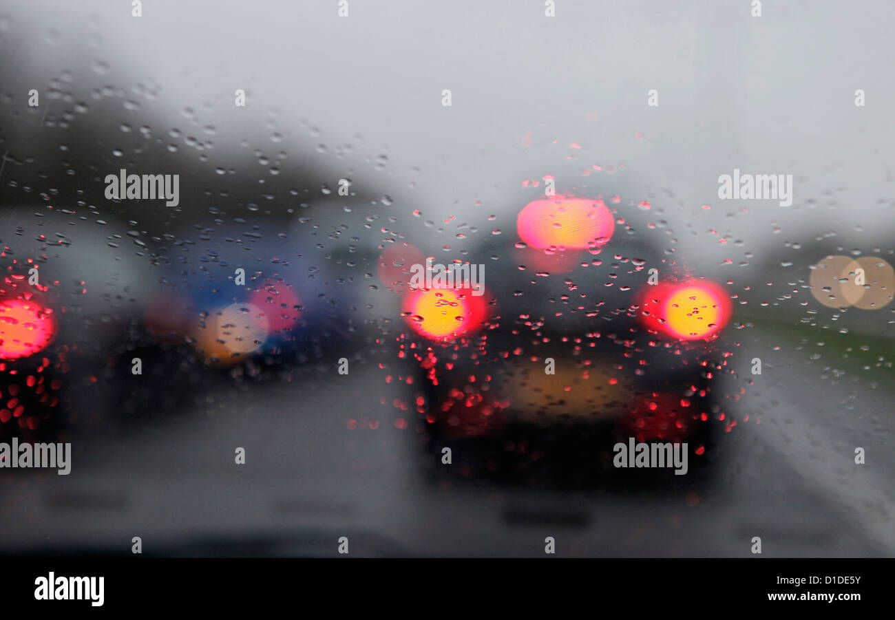 Feux arrière des voitures et de la pluie sur le pare-brise dans un matin tôt Rush hour traffic jam, England, UK Banque D'Images