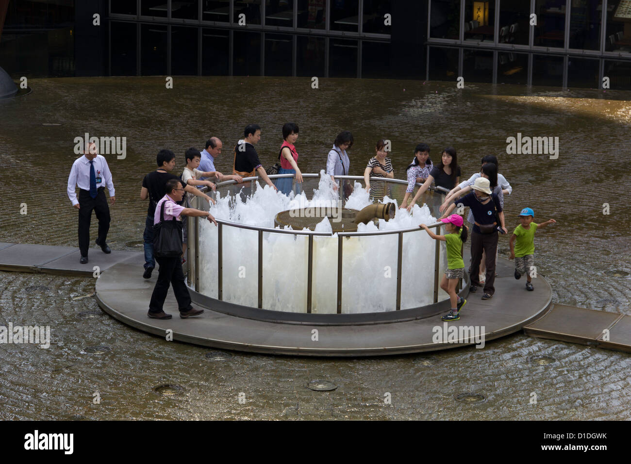 Les gens qui marchent autour de la fontaine de la richesse à Singapour. Il est considéré comme un bon signe si vous n'trois rondes de la fontaine. Banque D'Images