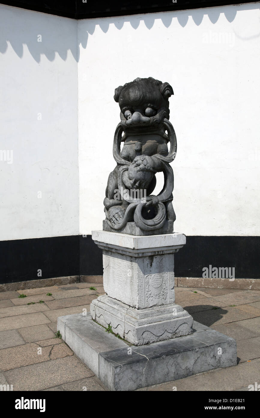 C'est une photo d'une statue de lion chinois dans la pierre de l'ancien temps. Il se tenir dans la rue près de l'entrée d'un temple Banque D'Images