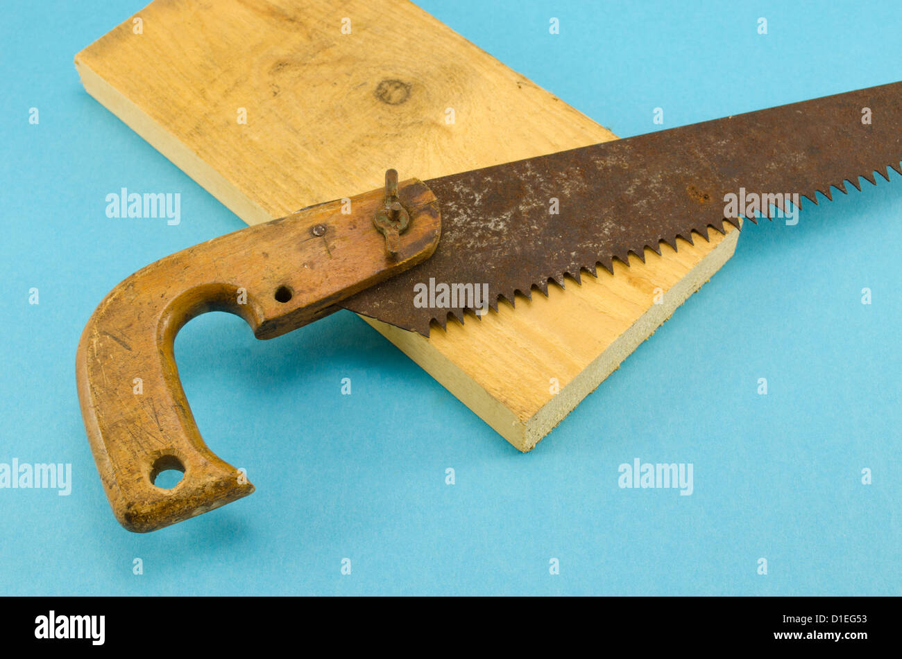 Scie égoïne rouillée rétro de l'outil à main et une partie de planche de  bois sur fond bleu Photo Stock - Alamy