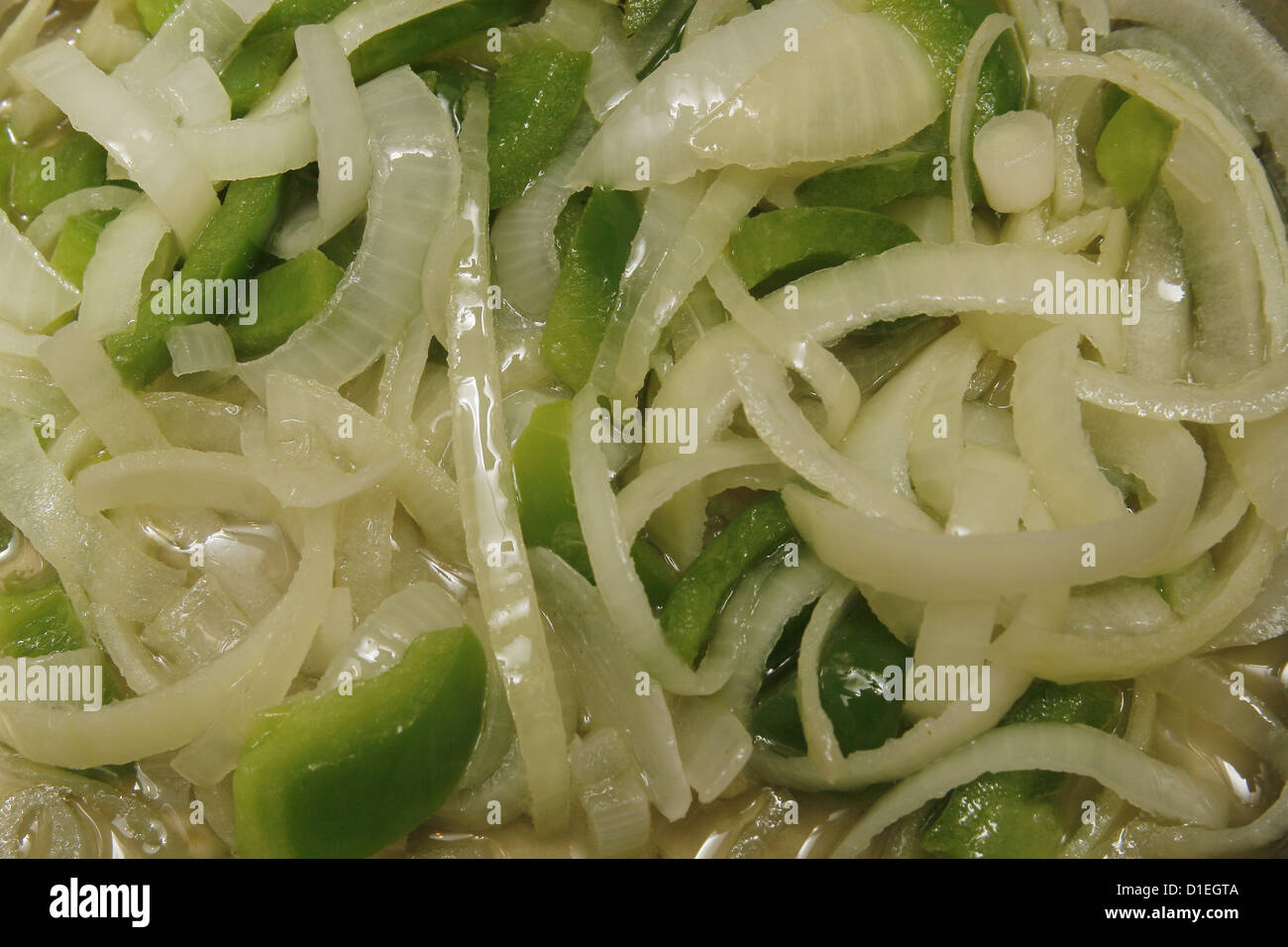 Poivrons verts, hachés et les oignons blancs la cuisson dans de l'huile végétale Banque D'Images