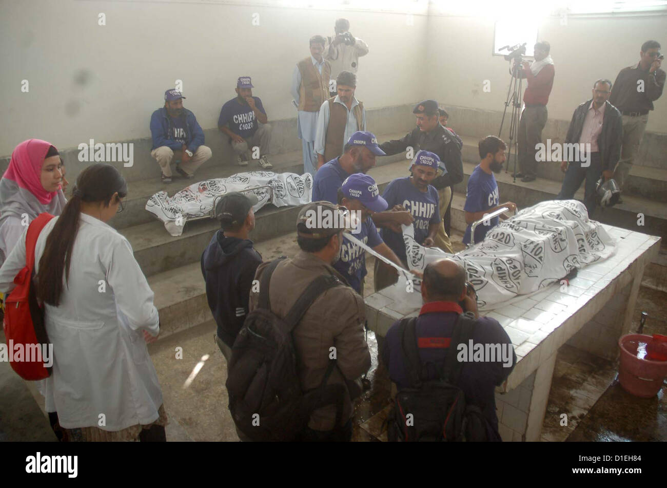 Les gens se rassemblent près de cadavres de femmes activistes anti-polio qui est abattu par des tireurs non identifiés dans différents domaines de Karachi, à l'hôpital Jinnah de Karachi mortuaires sur Mardi, 18 décembre 2012. Banque D'Images