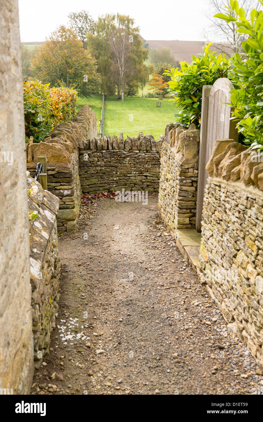 Sentier étroit entre les murs de pierre de Swinbrook à Widford Windrush Valley Banque D'Images