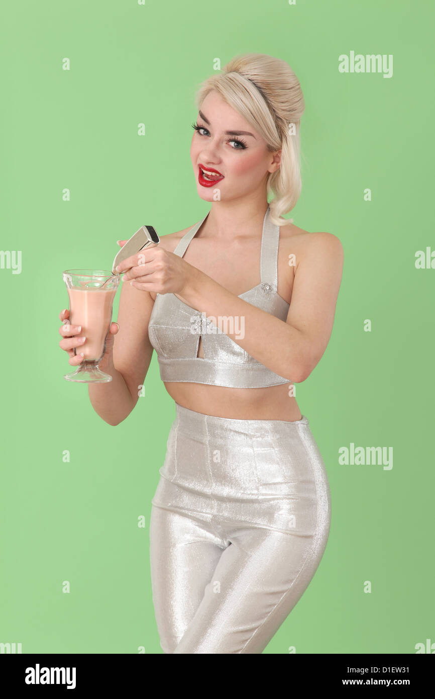 Femme en costume d'argent à l'ère spatiale en remuant un milk shake Banque D'Images