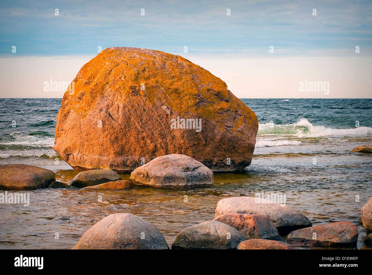 Gros rocher sur la plage dans la lumière du soir, avec beau ciel Banque D'Images