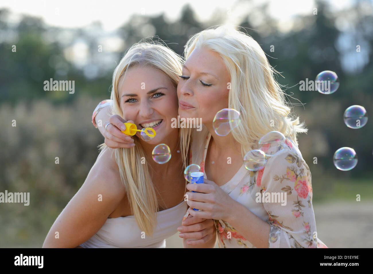 Deux jeunes femmes blondes heureux soufflant des bulles de savon en plein air Banque D'Images