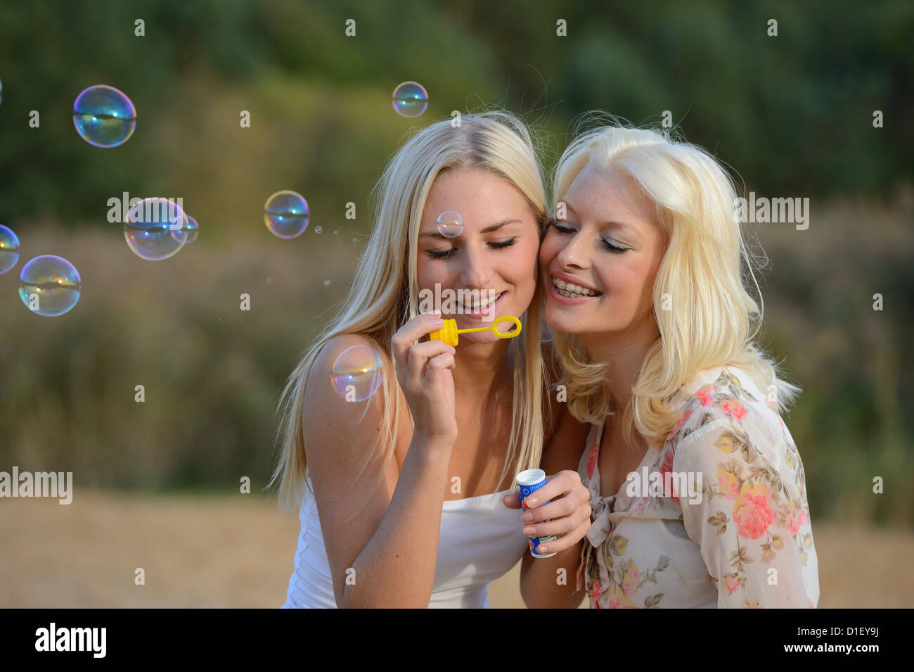 Deux jeunes femmes blondes heureux soufflant des bulles de savon en plein air Banque D'Images