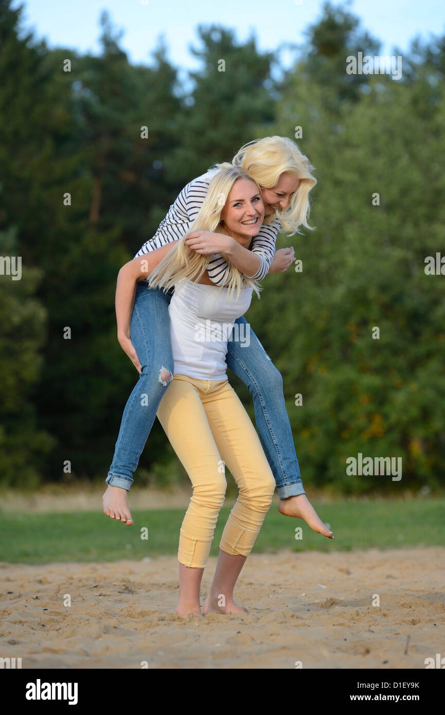 Jeune femme blonde portant son ami piggyback Banque D'Images