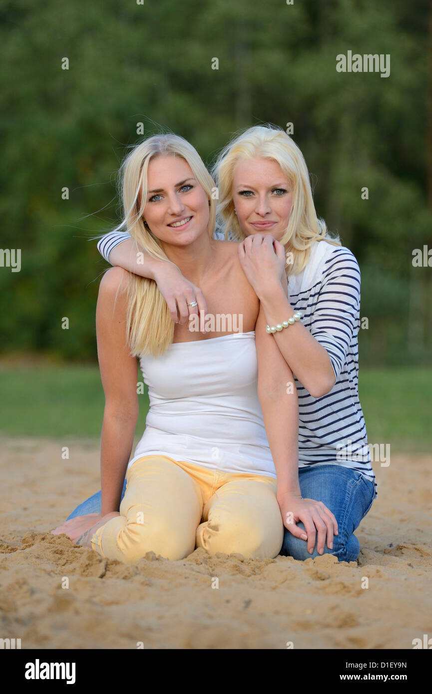 Deux jeunes femmes blondes heureux on sandy beach Banque D'Images