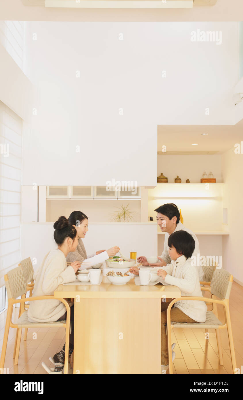 Famille de quatre personnes qui mangent à la table à manger dans le salon Banque D'Images