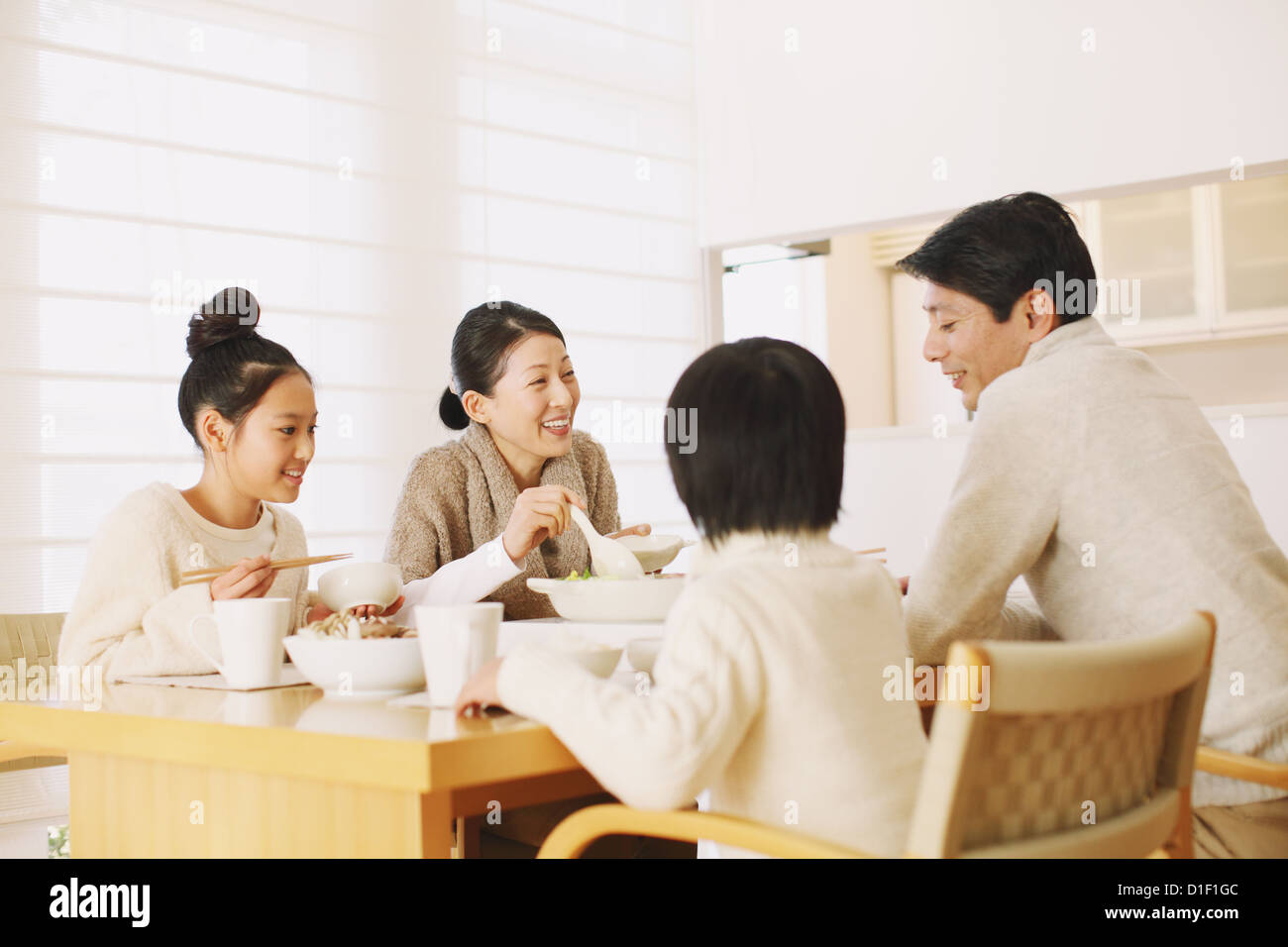 Famille de quatre personnes qui mangent à la table à manger dans le salon Banque D'Images