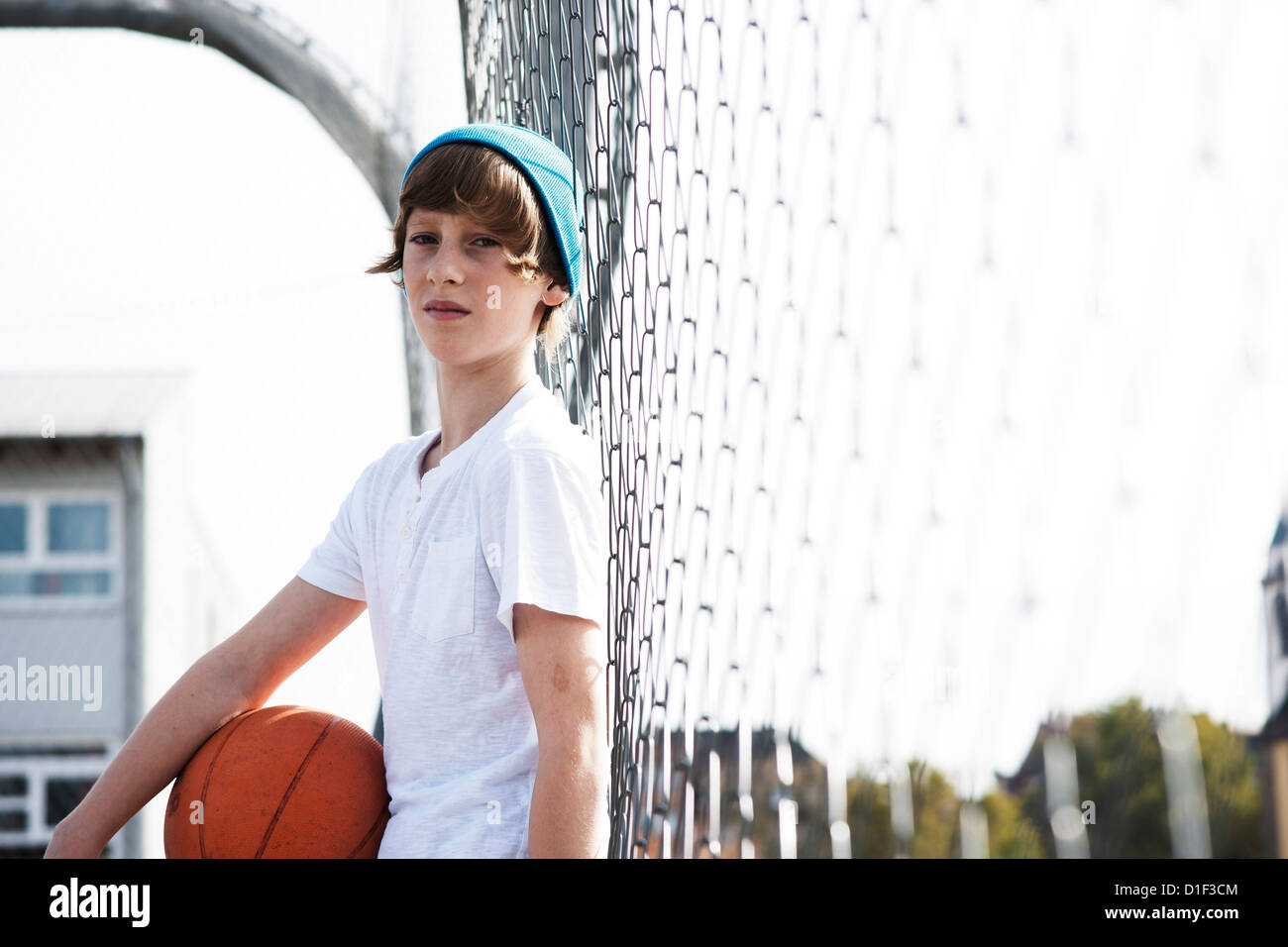 Garçon debout avec le basket-ball à fence Banque D'Images