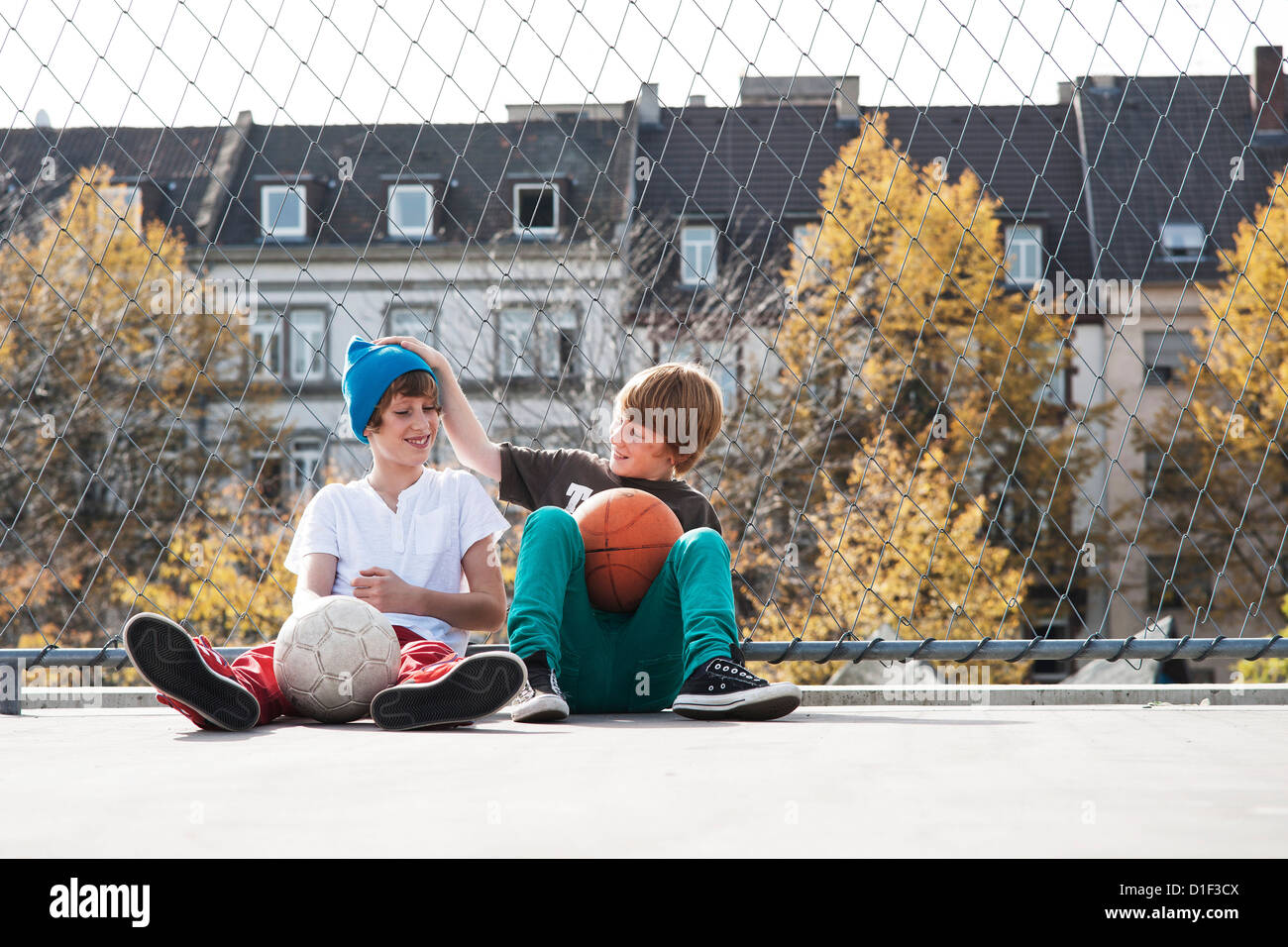 Deux garçons assis sur les boules avec sportsground Banque D'Images