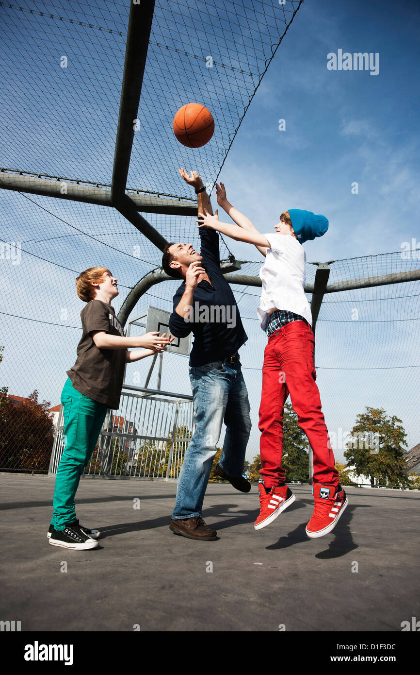 Son père et ses deux fils jouant au basket-ball Banque D'Images