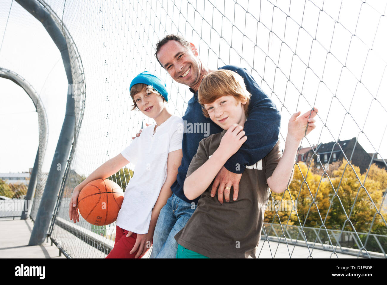 Son père et ses deux fils avec le basket-ball sur le terrain de sport Banque D'Images