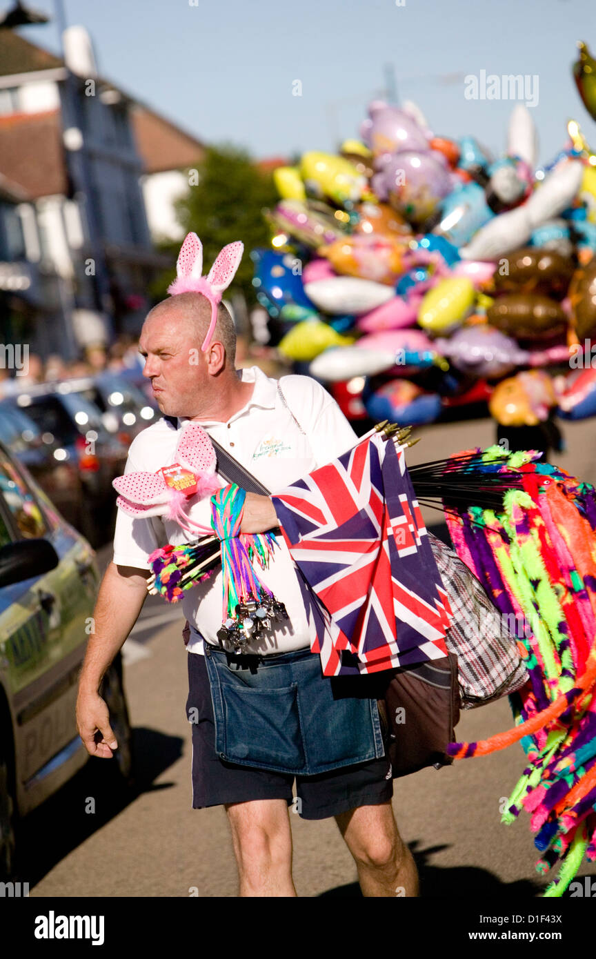 Carnaval homme nouveautés vendeur portant des oreilles de lapin portant des drapeaux Union Jack, de sifflets et de serpents à fourrure Banque D'Images