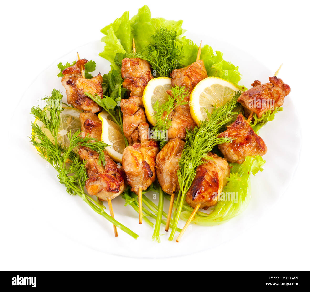 Sur les brochettes de poulet avec le citron et les feuilles de salade sur une assiette, isolé sur fond blanc Banque D'Images