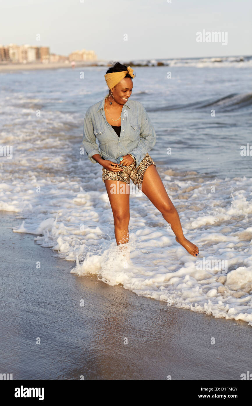 Black woman wading in ocean on beach Banque D'Images