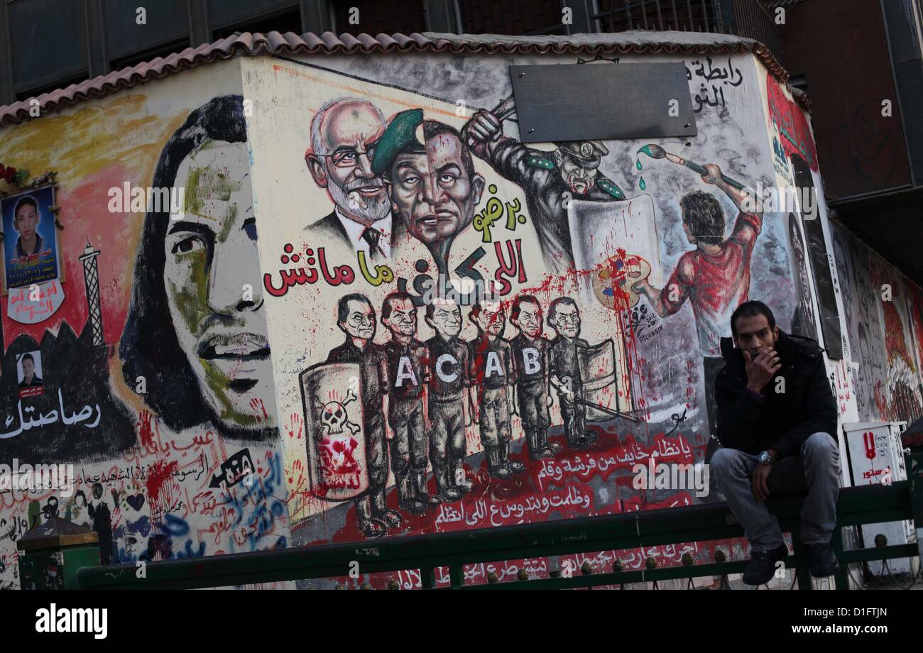 19 déc., 2012 - Le Caire, Le Caire, Égypte - un siège égyptien au palais présidentiel et anti-Morsi graffiti est visible sur le mur du palais derrière lui au Caire, 18 décembre 2012. L'opposition de l'Egypte ont organisé des rassemblements dans tout le pays mardi pour protester contre le projet de constitution référendum, après le ministère de la Justice a ordonné une enquête sur les allégations d'irrégularités de vote au cours du samedi premier tour de scrutin sur le document (Image Crédit : © Ashraf Amra/APA Images/ZUMAPRESS.com) Banque D'Images