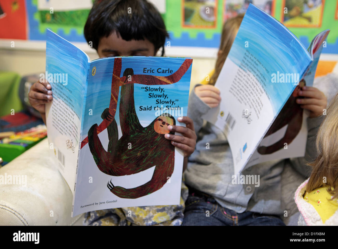 Deux élèves filles junior primaire absorbé par la lecture de livres, London, UK Banque D'Images