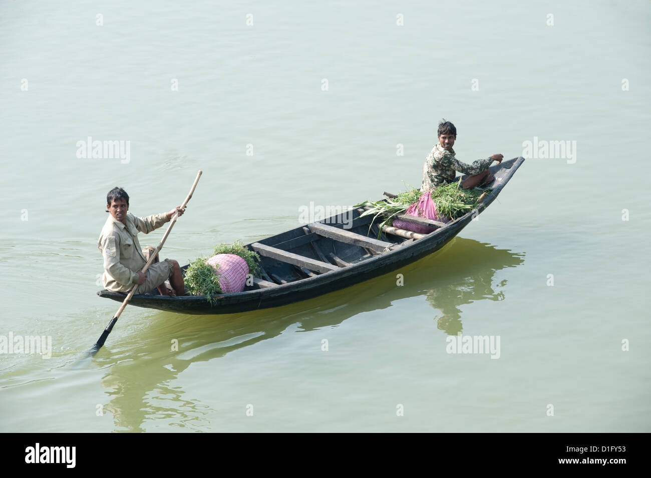 Les hommes barques à un bateau en bois le long de la rivière Hugli, transportant des paquets de la luzerne au marché, près de Kolkata, West Bengal, India Banque D'Images