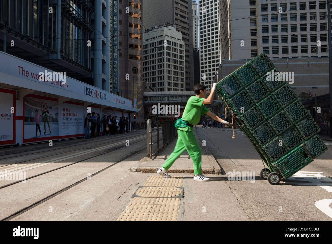 Un chariot pousse les travailleurs chargés de l'eau en bouteille en face de la banque HSBC siège à Hong Kong. Banque D'Images
