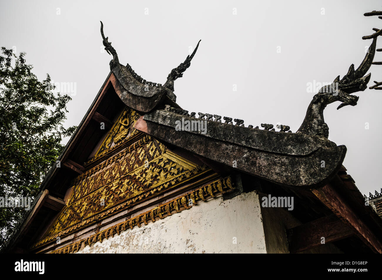 Détail du toit de Chomsi Stupa Luang Prabang Laos // LUANG PRABANG, Laos — le fronton et les figures ornementales de chofah richement décorées ornent le toit de ce Chomsi, un stupa bouddhiste vénéré situé sur le sommet du mont Phousi. Construit en 1804, le stupa doré sert de site religieux important pour les pratiquants bouddhistes locaux et les pèlerins. Le mont Phousi s'élève à environ 100 mètres au-dessus du centre historique de la ville, offrant une position dominante au-dessus de la confluence du Mékong et du Nam Khan. Que Chomsi est parmi les monuments religieux les plus visités à Luang Prabang, dessin Banque D'Images